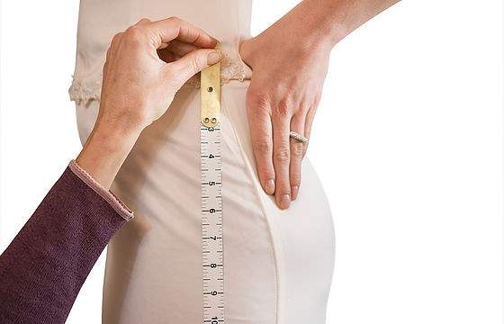 The side of a woman's hip being measured with a tape measure